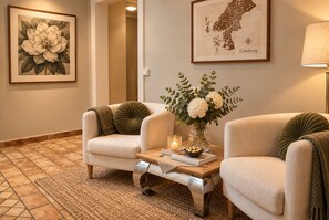 A room with two armchairs, a table with a vase of flowers, a framed map, and a lamp. - 5:ans Bed & Breakfast (Gothenburg)
