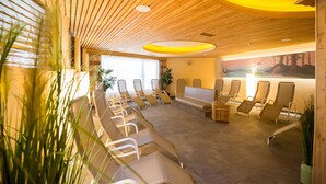 Habitación iluminada por el sol con techos de listones de madera, una hilera larga de tumbonas y un ventanal que proporciona luz natural.