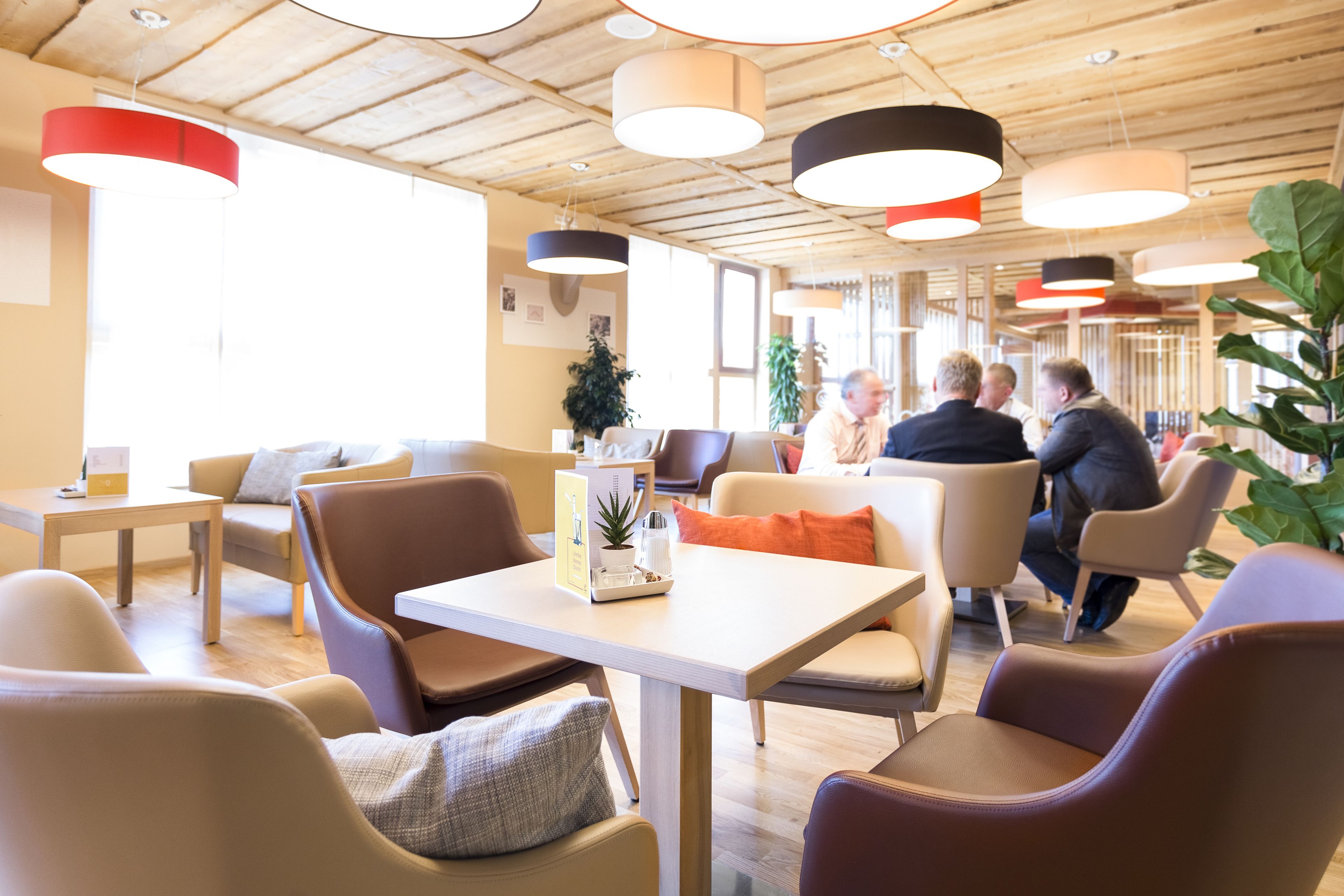 A modern interior with wooden ceilings, multiple seating areas, and pendant lighting.