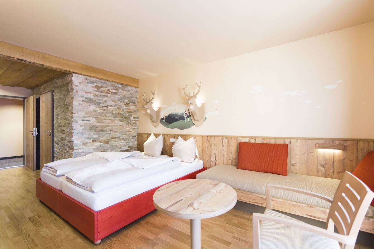 Una habitación de hotel moderna con cama, zona de estar y una decoración de cabeza de venado montada en la pared.