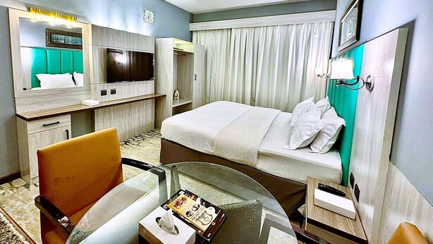 Una habitación de hotel con cama, televisor, escritorio y una silla.