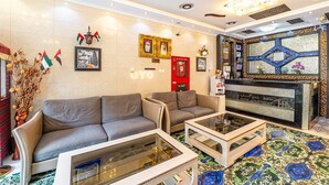 Un hall con sofás, un mostrador de recepción y una pared decorativa con banderas y cuadros.