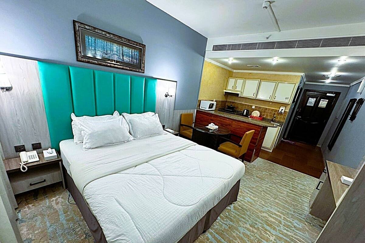 A hotel room with a bed, a desk, and a kitchenette.