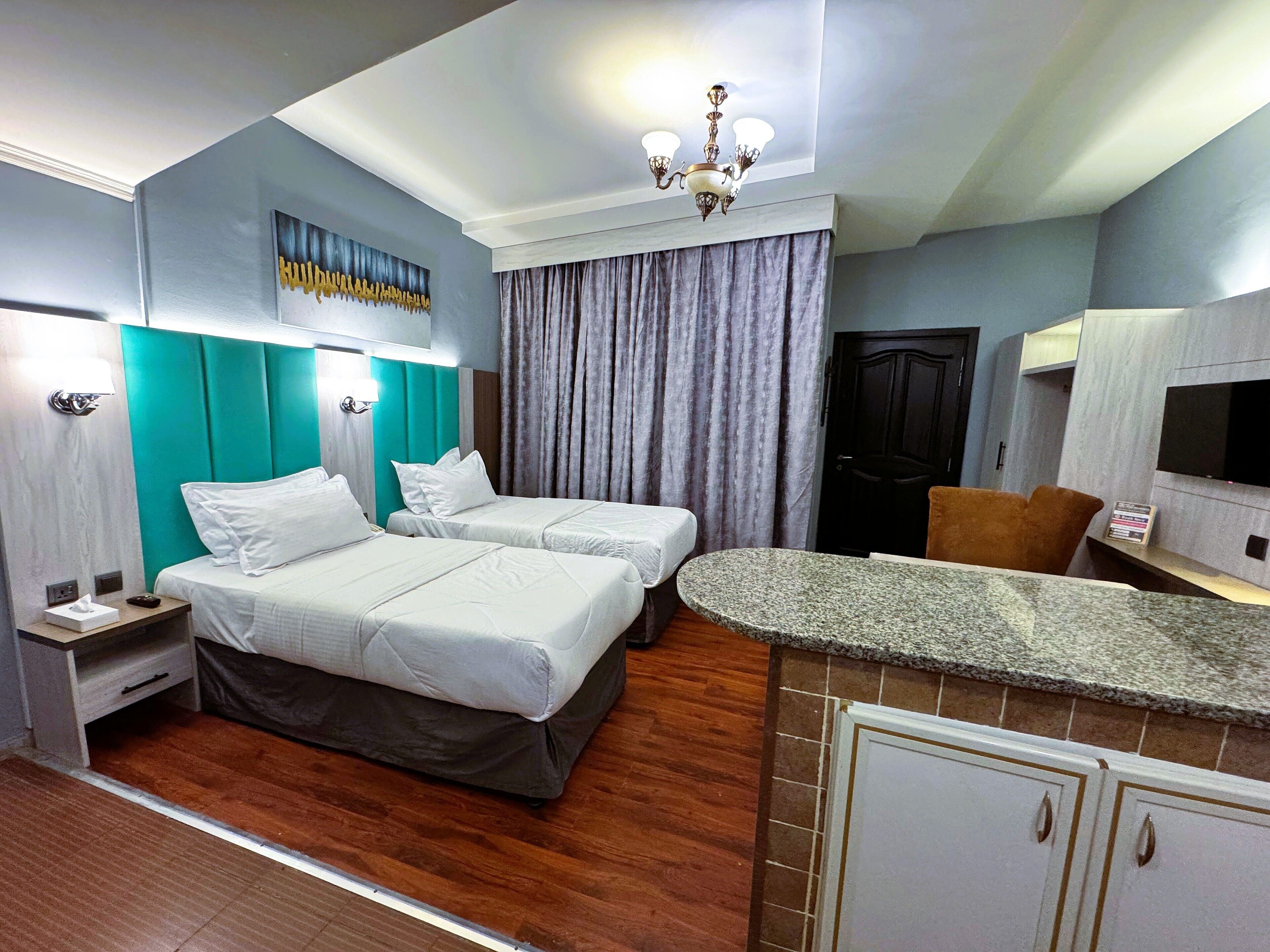 Une chambre d’hôtel avec deux lits, une petite kitchenette, une télévision et une porte.