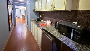 Una cocina con microondas, lavamanos y armarios.