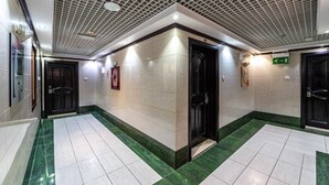 Un pasillo moderno con techo estampado, pisos de baldosas y puertas negras.