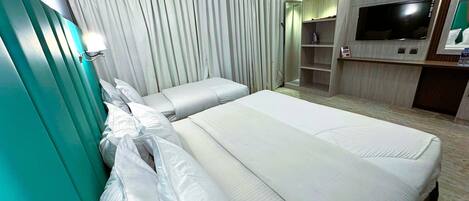 A hotel room with two beds, a TV, a wardrobe, and a curtain.