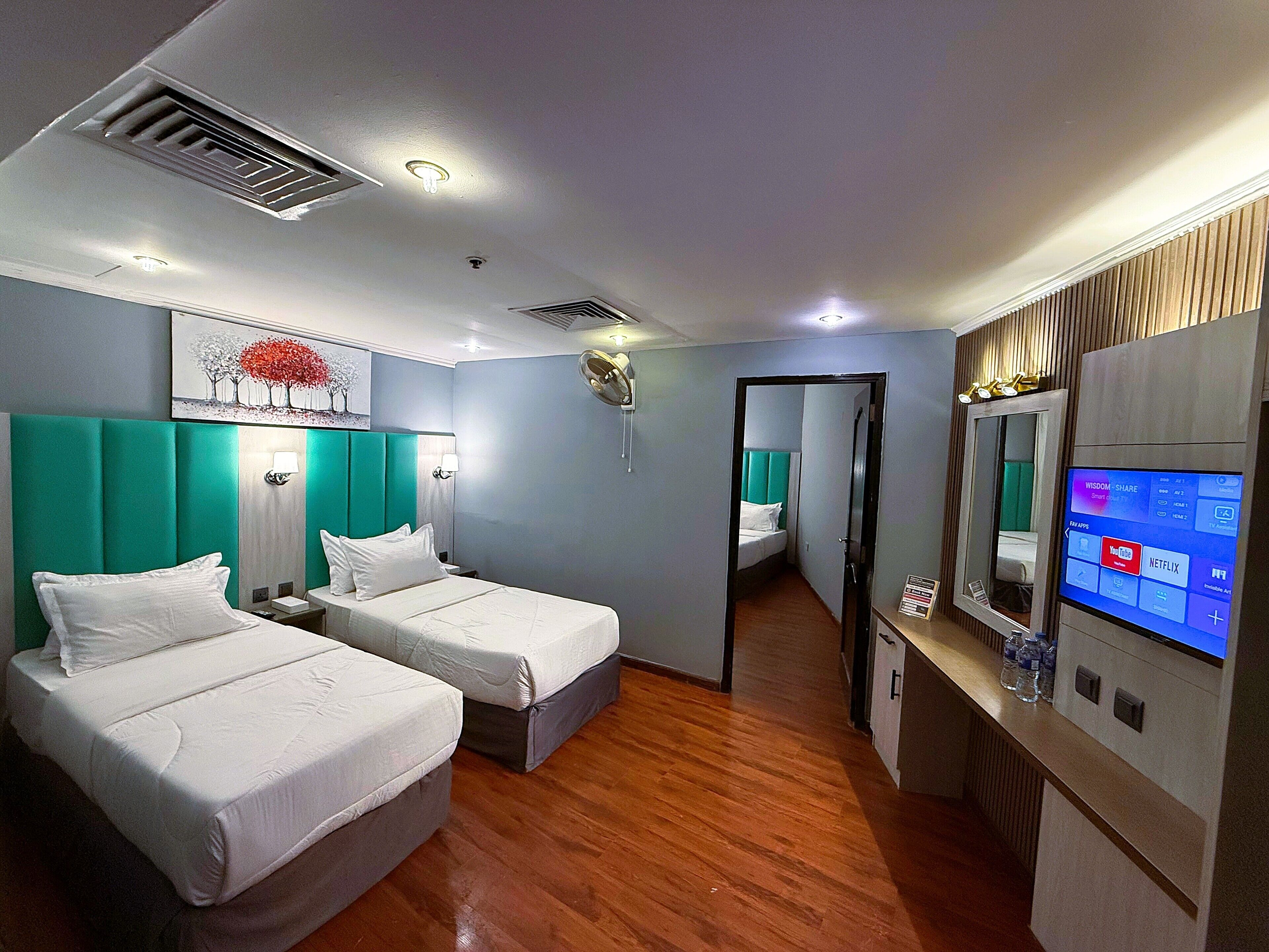 Quarto de hotel com duas camas, uma televisão e um espelho.