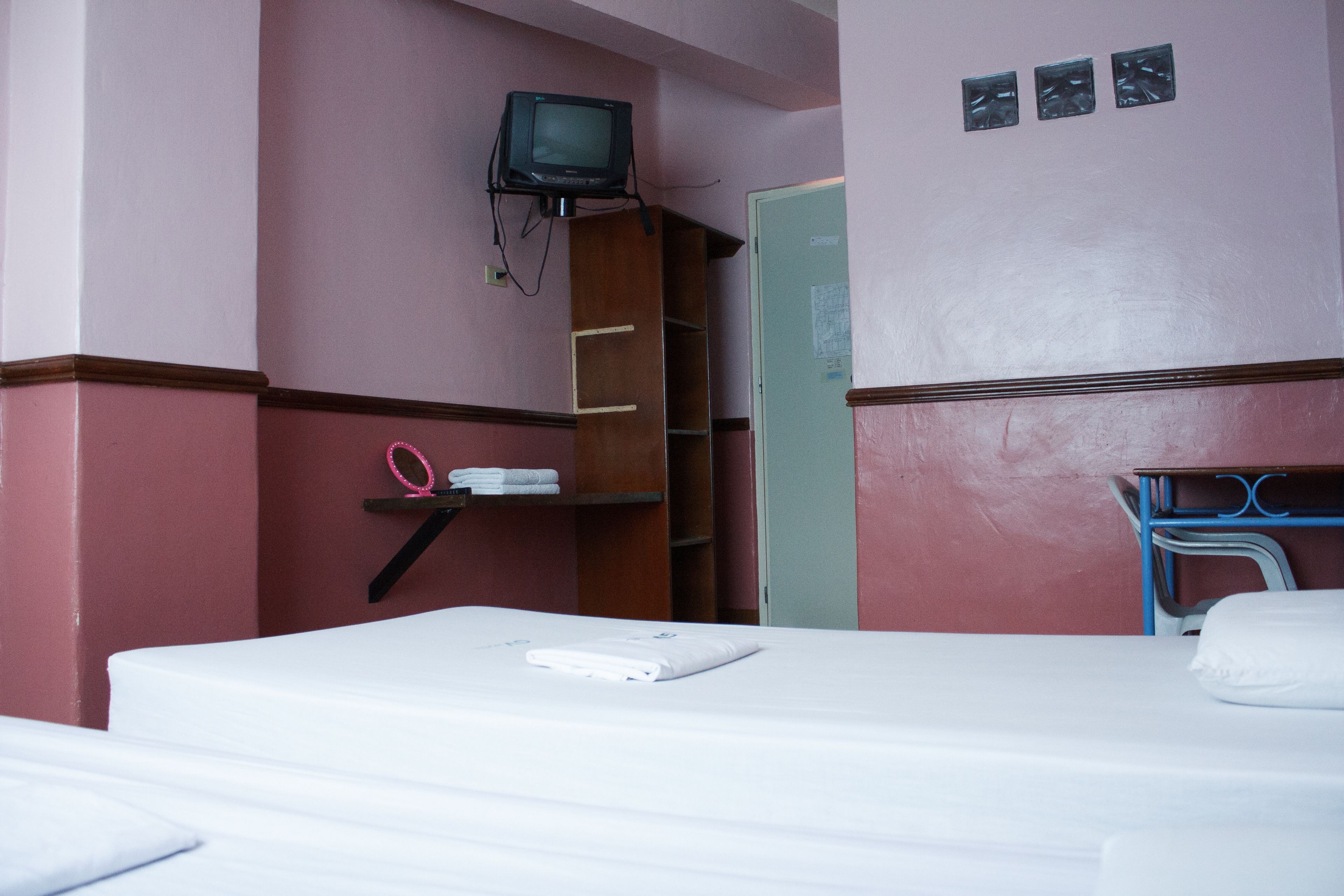 Una habitación de hotel con cama, televisión montada en la pared, armario y escritorio con silla.