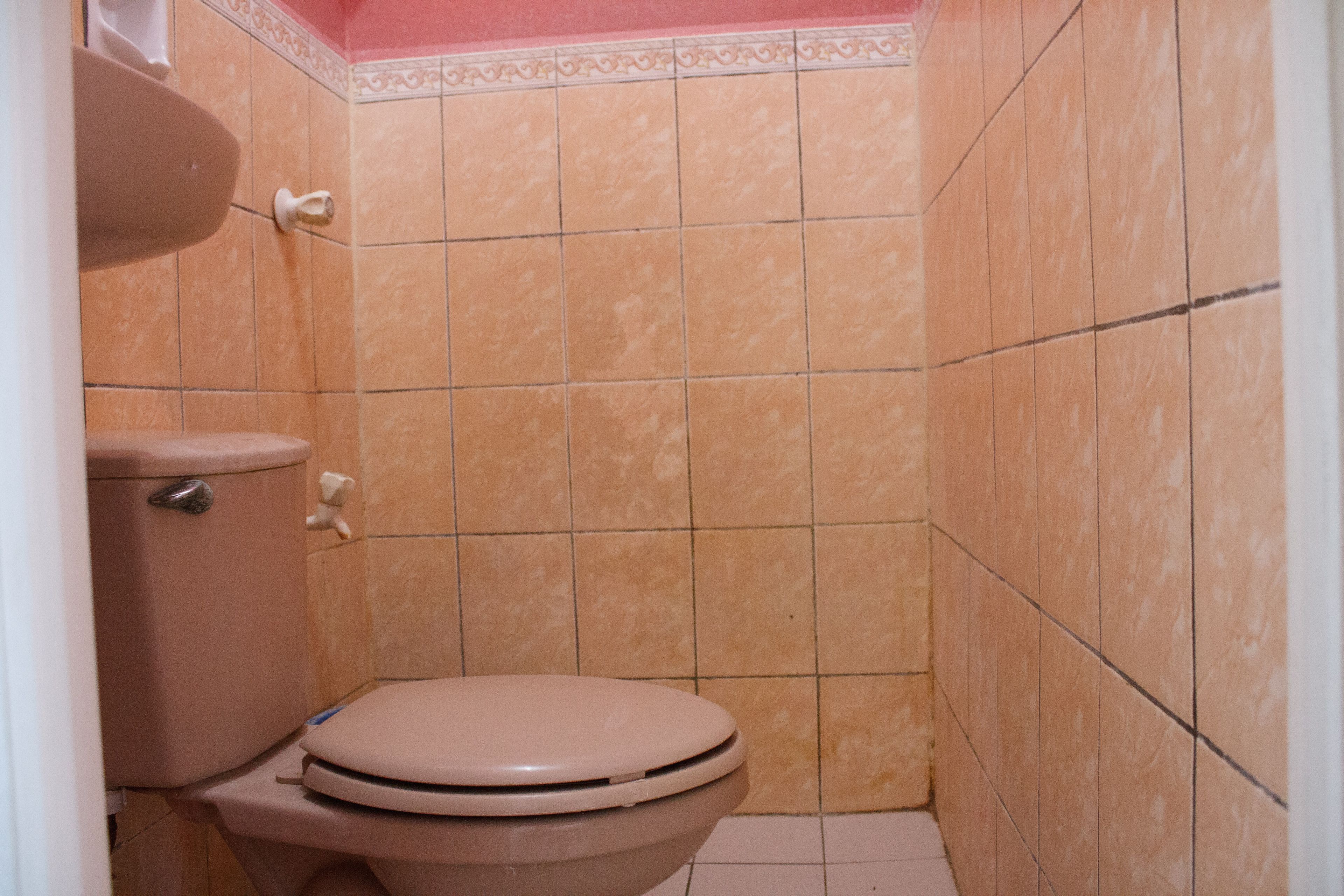 A small bathroom with a toilet, a sink, and tiled walls.