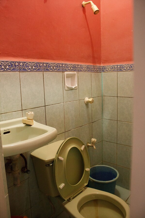 Un baño con inodoro, lavabo y un cubo azul.