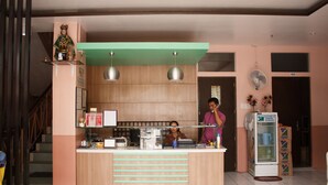 A reception area with a counter, two pendant lights, a statue on a shelf, a refrigerator, and a staircase. - GV Hotel Maasin (Maasin City)