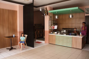 Un café con un mostrador de madera, un niño sentado en una mesa y una persona de pie detrás del mostrador.