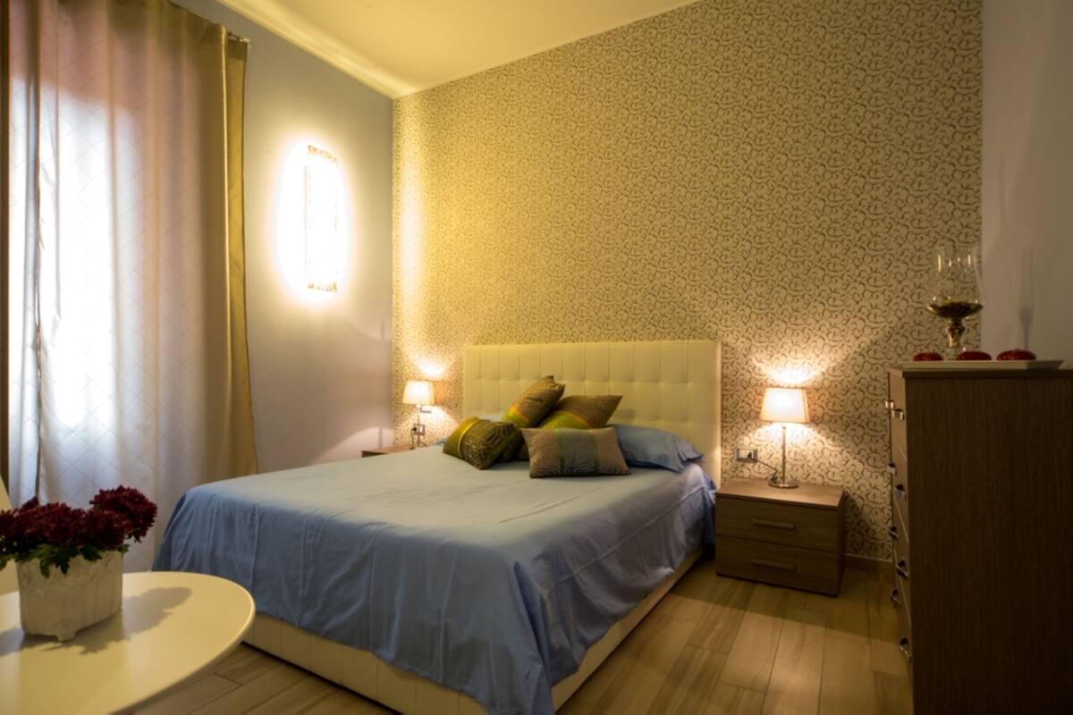 A neatly arranged bedroom with a bed, bedside tables, and a nightstand.