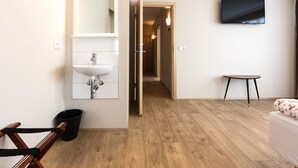 Une salle de bain moderne avec un lavabo, un miroir et un téléviseur fixé au mur.