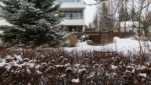 Un bâtiment à deux étages doté d’un balcon, entouré d’arbres et d’arbustes couverts de neige.