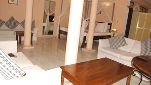 Una habitación de hotel con un sofá blanco, una mesa de centro de madera y una cama con dosel.