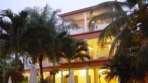 Un hotel con piscina, zona de estar al aire libre y palmeras.