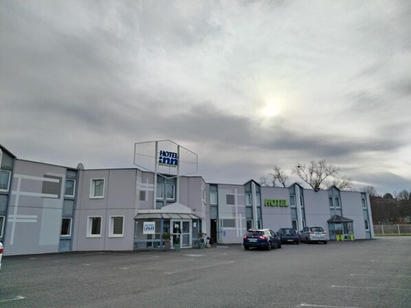 A hotel with a modern design, featuring a prominent sign and a parking lot with several cars.