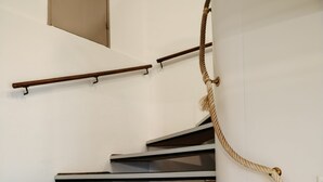 Una escalera con peldaños blancos y negros, barandilla y una barrera de cuerda.