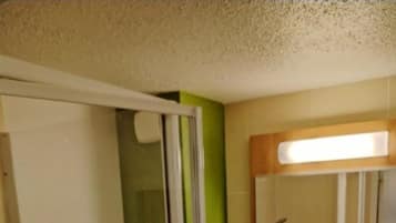 Un baño compacto con cabina de ducha de vidrio, inodoro, lavamanos con espejo y un cubo de basura.