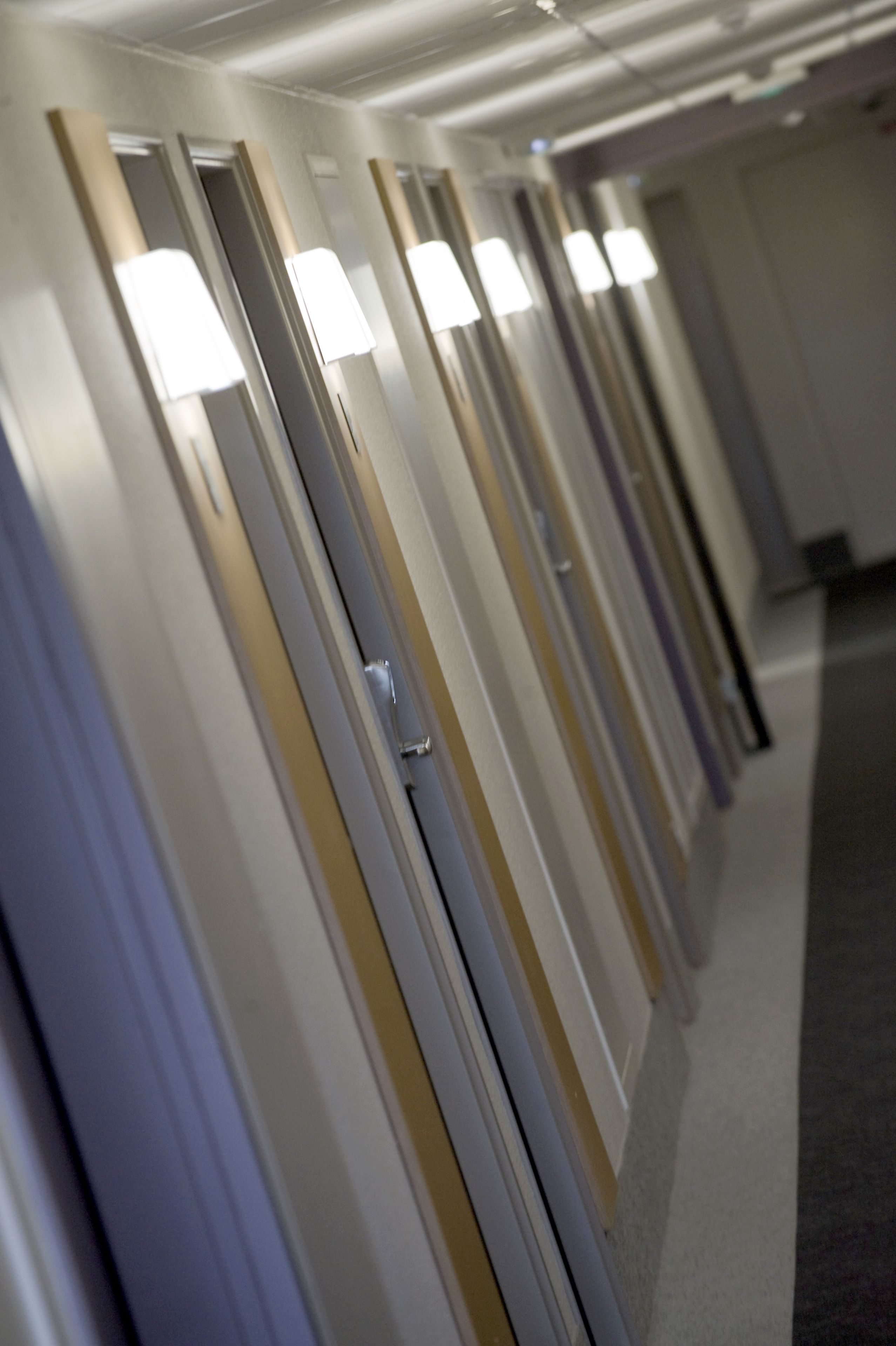 Um corredor com portas, cada uma com uma luz acima.