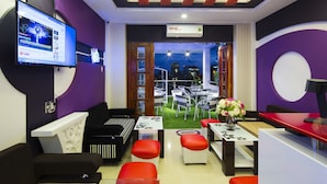 A modern hotel lobby with a flat-screen TV, a reception desk, and a seating area with red and white chairs. - Hoang Dung Hotel – Hong Vina (Ho Chi Minh City)