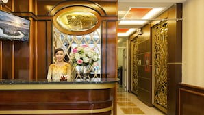 A reception desk with a floral arrangement and a framed photo of a cityscape. - Hoang Dung Hotel – Hong Vina (Ho Chi Minh City)