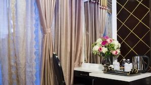 A hotel room with a desk, a chair, a vase with flowers, a kettle, and a tray with items. - Hoang Dung Hotel – Hong Vina (Ho Chi Minh City)