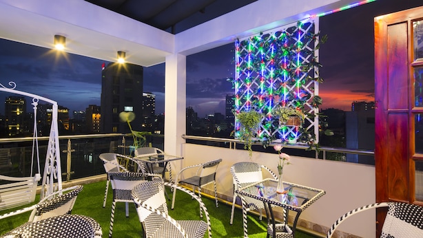 A rooftop terrace with outdoor seating, a decorative light wall, and a city view at dusk. - Hoang Dung Hotel – Hong Vina (Ho Chi Minh City)
