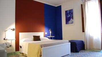 A bedroom with a bed, bedside table, lamp, and a window with curtains.