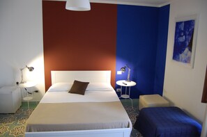 A hotel room with a large bed, bedside tables, a small stool, and a blue accent wall. - Helios B&B (Castellammare del Golfo)