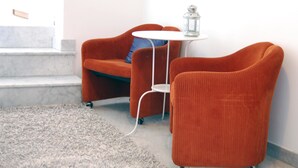 A room with a grey carpet, a white round table, and two orange armchairs.