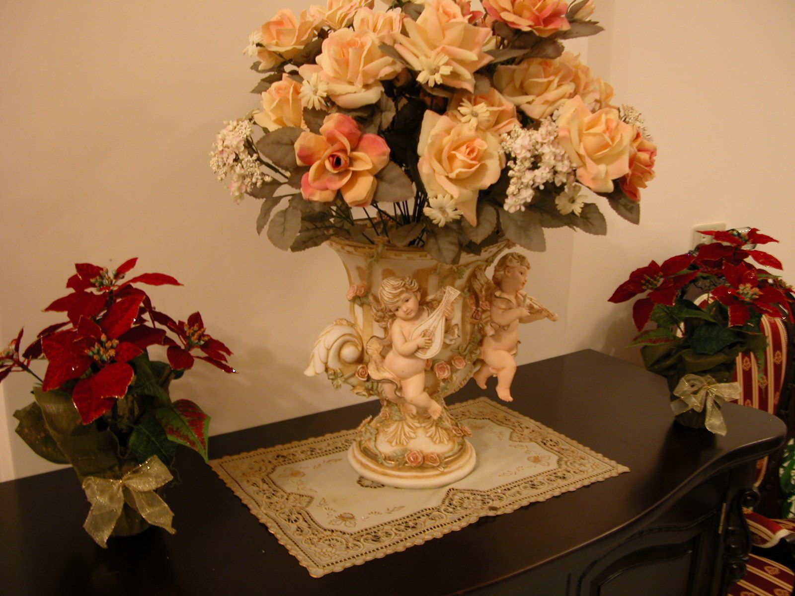 Une table ornée d’un vase décoratif contenant des fleurs et de deux plantes en pot.