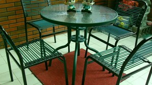 Une table ronde avec quatre chaises, deux statuettes posées sur la table et un tapis rouge sur le sol.