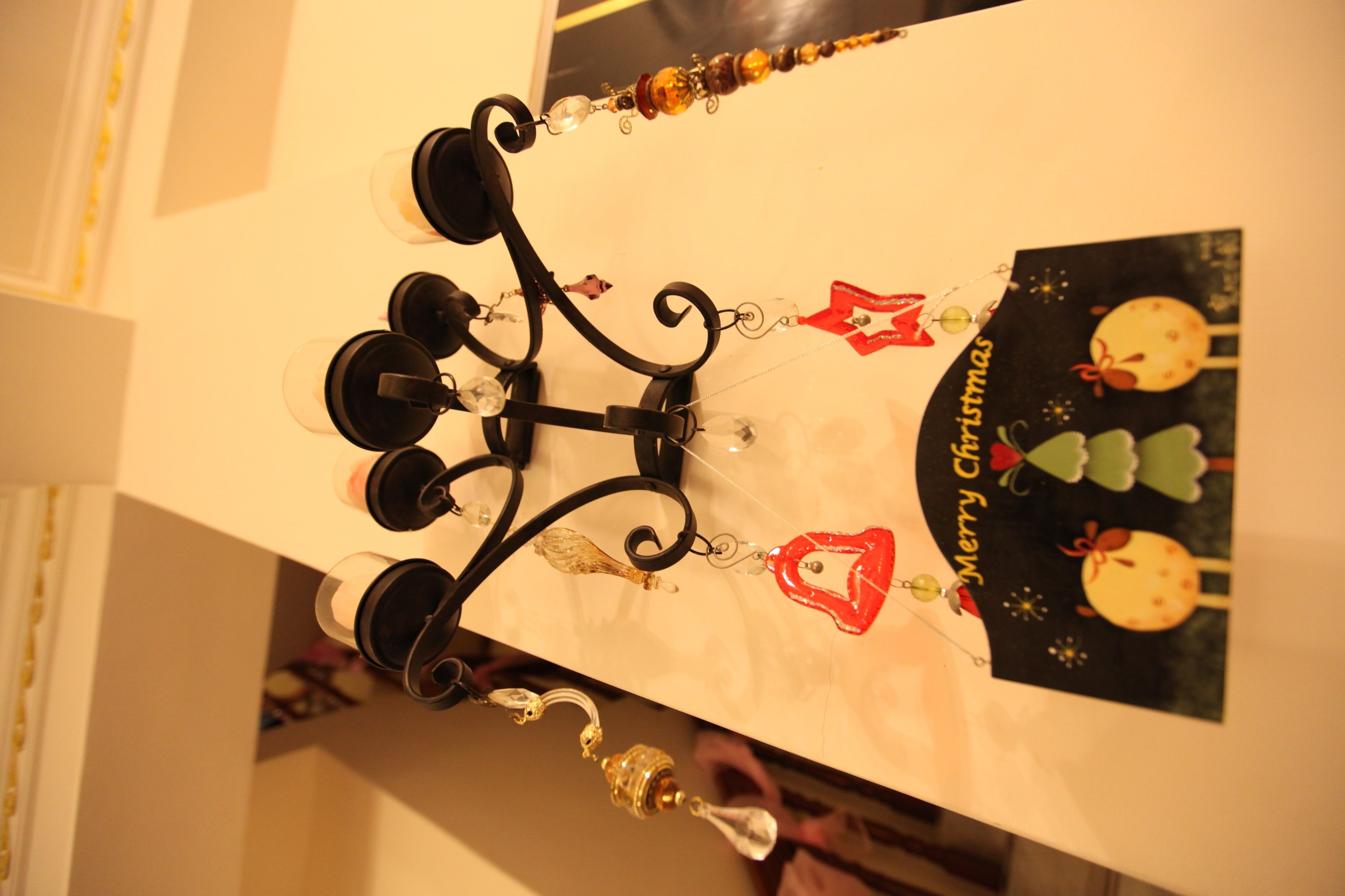 A chandelier with multiple candle holders and a card with a Christmas theme.
