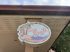 A sign for "Sea Beach Koh Larn Island" with a palm tree and sun design. - Sea Beach Koh Larn (Koh Lan)