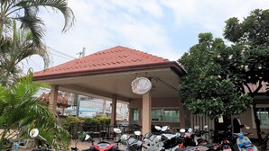 A covered parking area with multiple motorcycles parked under a red roof. - Sea Beach Koh Larn (Koh Lan)