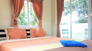 A bed with a striped headboard, multiple pillows, and a blue towel. - Sea Beach Koh Larn (Koh Lan)