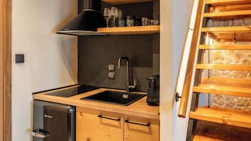 Una cocina con armarios de madera, un refrigerador de acero inoxidable y una estufa empotrada.