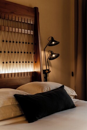 Una cama bien hecha con cabecera de madera y dos lámparas de noche.