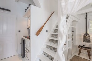 A staircase with patterned steps, a wooden bat, and a woven basket. - Captain Zeppos (Milos)