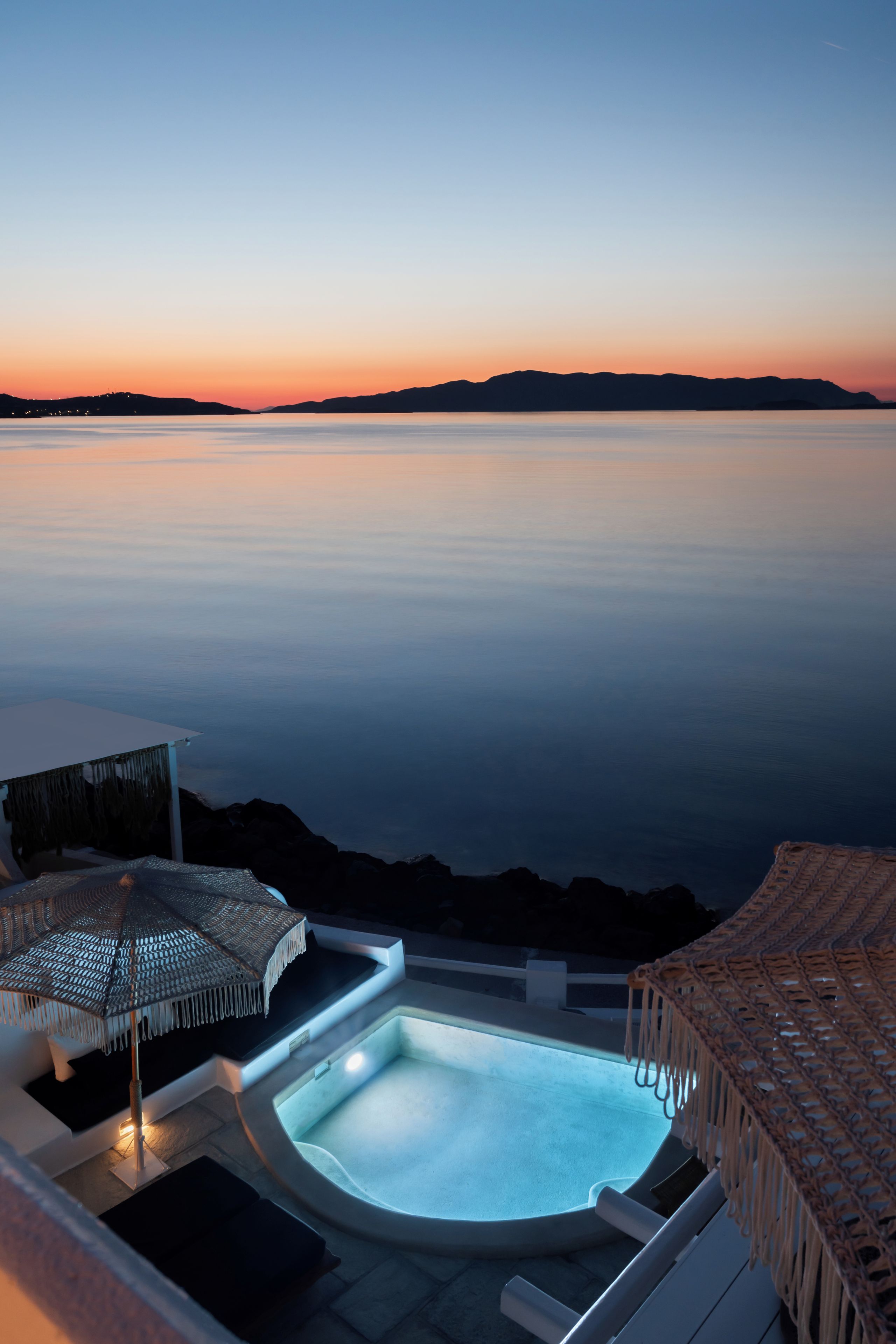 Ein Poolbereich mit Blick auf das Meer bei Sonnenuntergang.