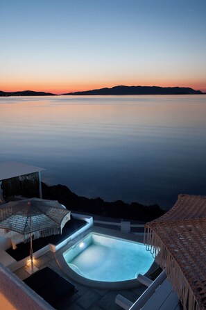 Zona de piscina con vista al mar al atardecer.