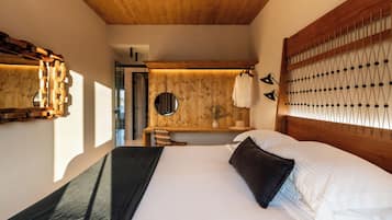 Un dormitorio con techo de madera, una cama con ropa de cama blanca, una mesita de noche con espejo y una lámpara de pared.
