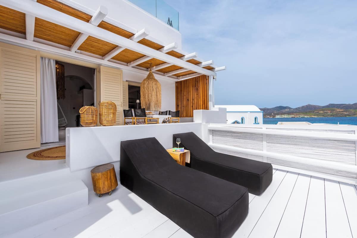 Ein moderner Außenbereich mit schwarzen Lounge-Stühlen, einem Holztisch und Korbwannen.