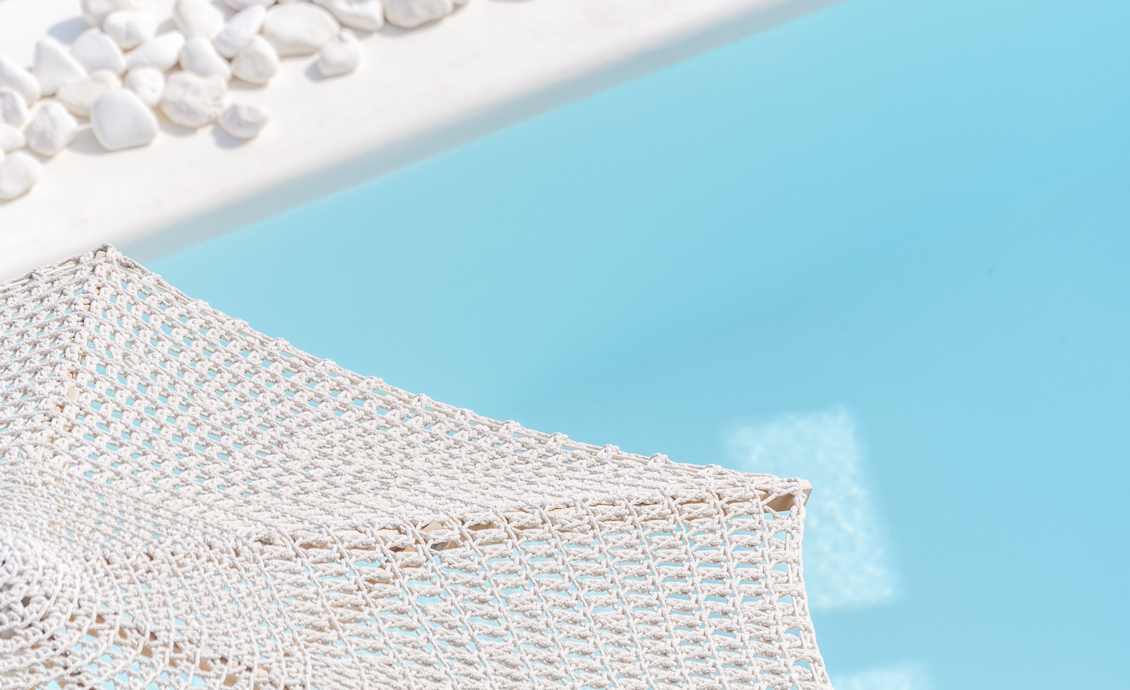 Een witte gehaakte strandstoel met een helder uitzicht op de lucht en een zwembad.