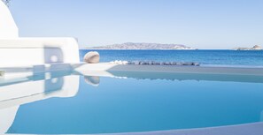 A clear blue pool with white stones and a white building, reflecting the sky and water. - Captain Zeppos (Milos)
