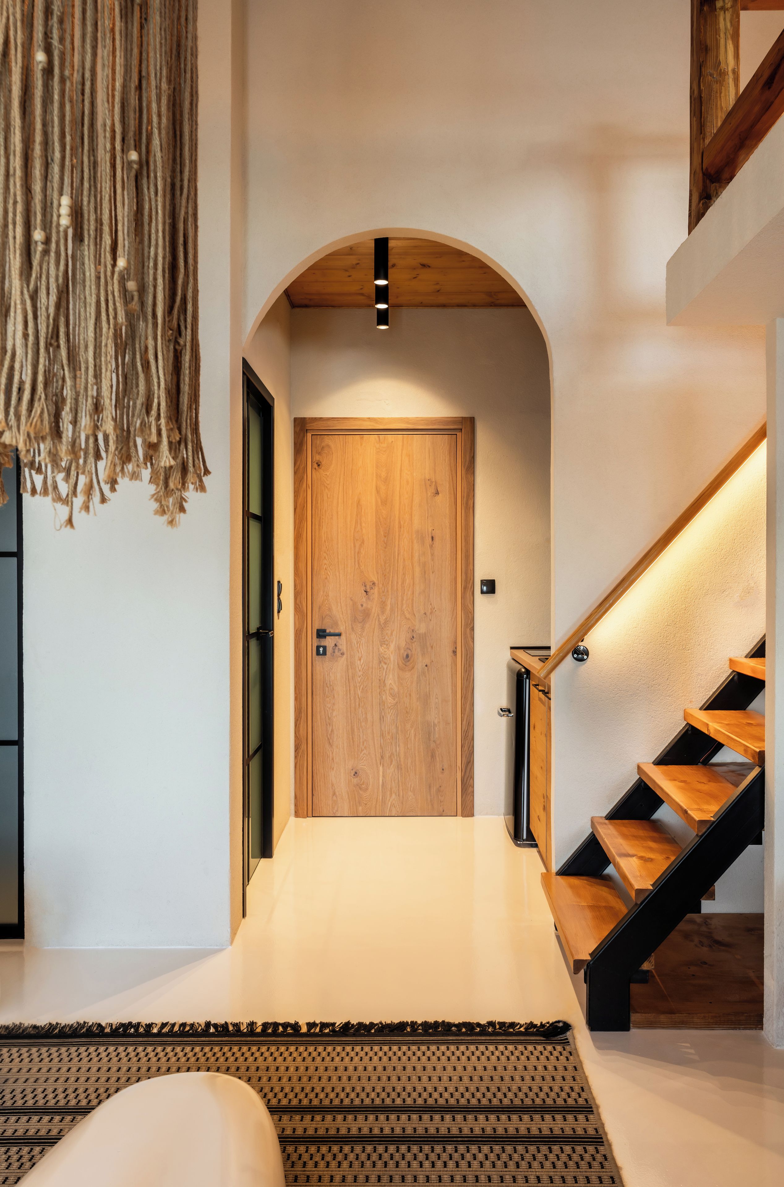 Un interior moderno con una puerta de madera, una escalera y un colgador de luz.