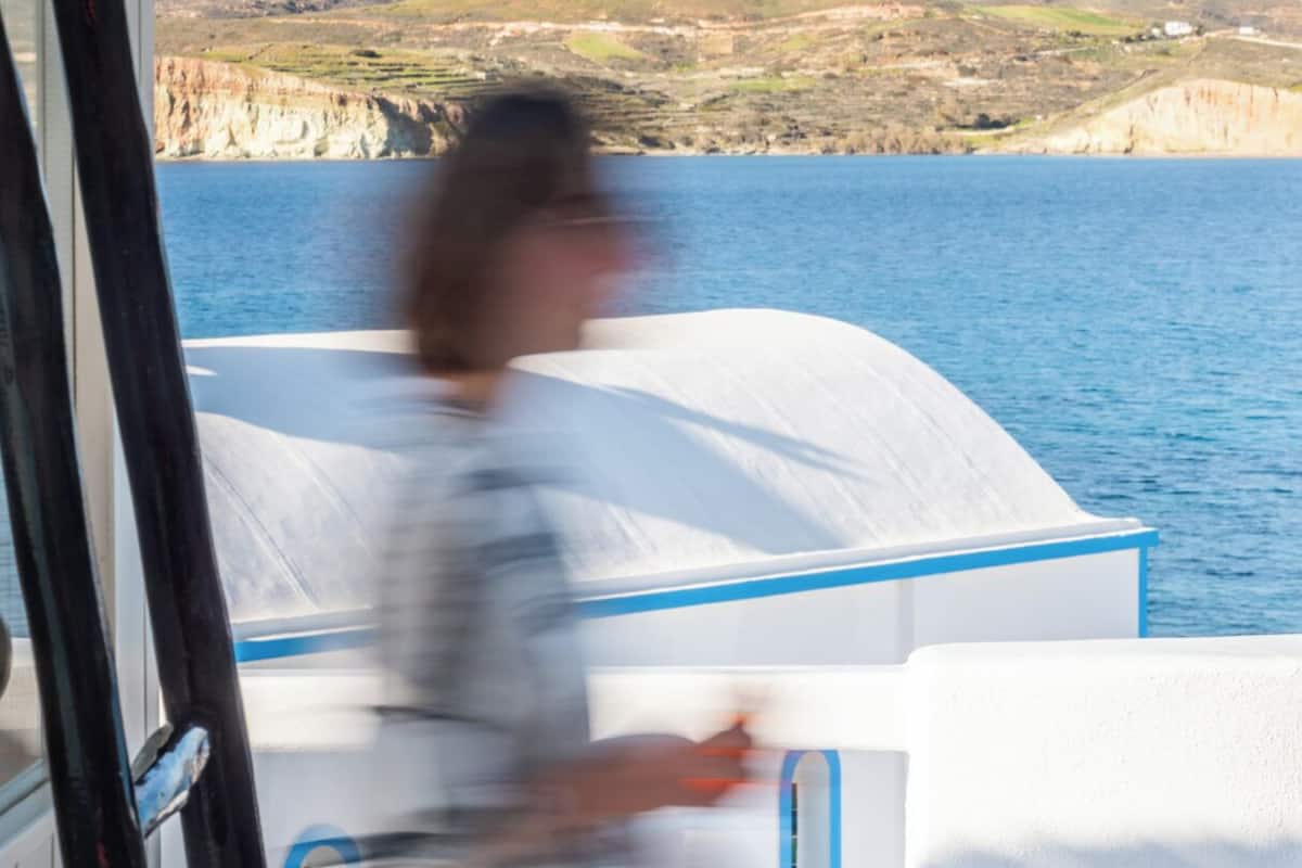 Eine Person geht über das Deck eines Bootes, im Hintergrund eine gebirgige Landschaft.